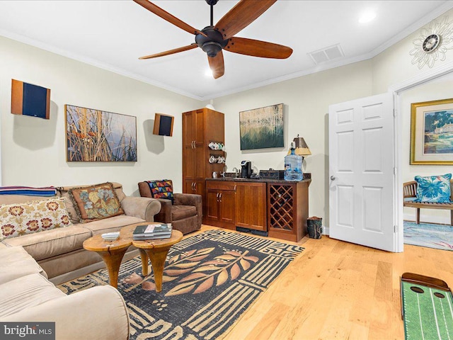 living area with baseboards, light wood-type flooring, a ceiling fan, crown molding, and visible vents