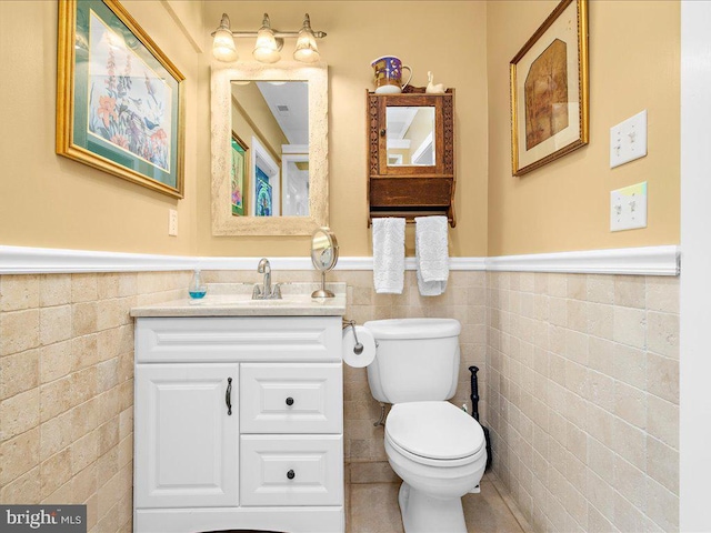 bathroom with toilet, tile walls, and a wainscoted wall