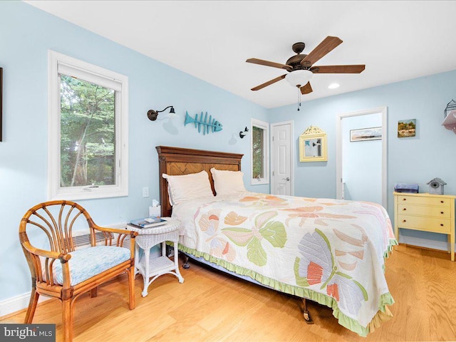 bedroom with light wood-style flooring, ceiling fan, and baseboards