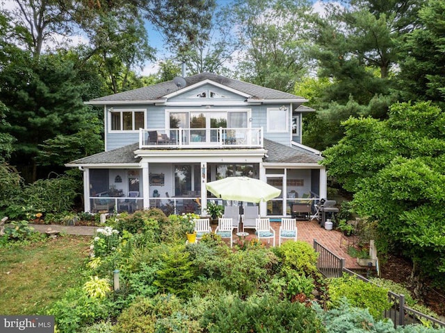 back of property with a sunroom and a balcony