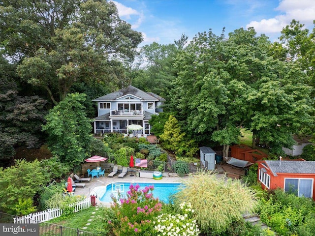 back of house with a patio area, a fenced backyard, a fenced in pool, and a balcony