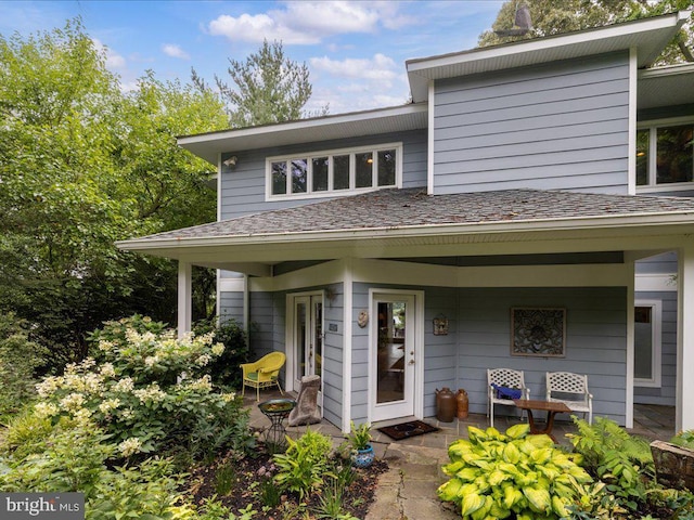 entrance to property featuring roof with shingles and covered porch