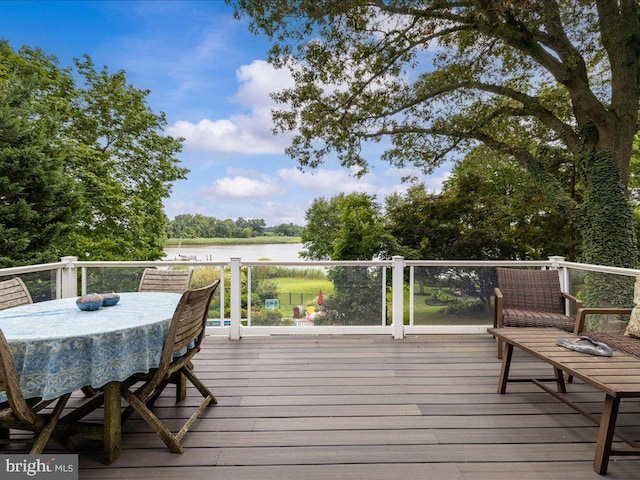 wooden deck with a water view and outdoor dining space