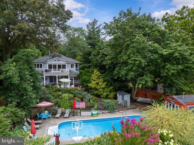 outdoor pool featuring a patio, an outbuilding, a shed, and fence