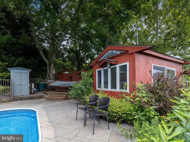 view of swimming pool with a patio area, a fenced in pool, a wooden deck, and an outdoor structure