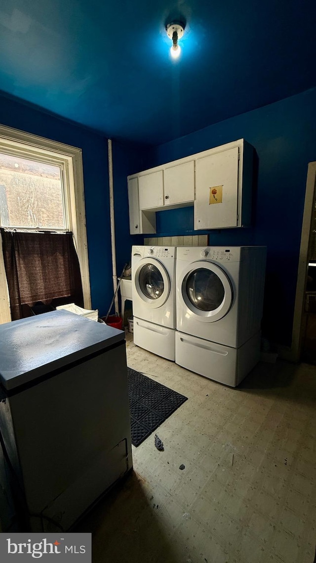 laundry area featuring separate washer and dryer, cabinet space, and tile patterned floors