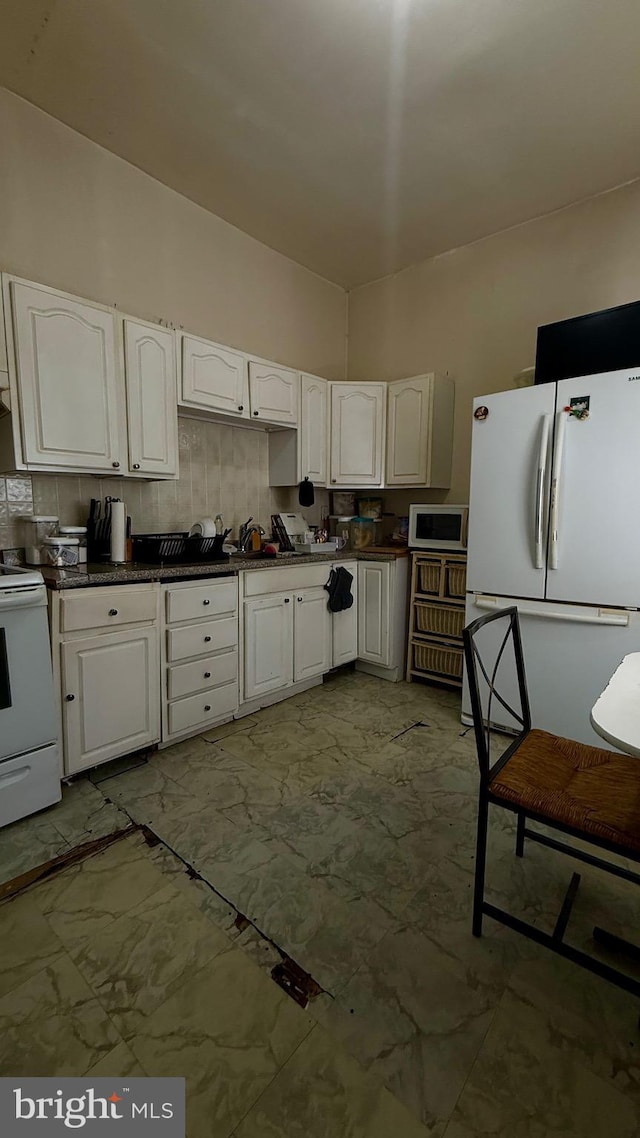 kitchen with white appliances, white cabinetry, and dark countertops