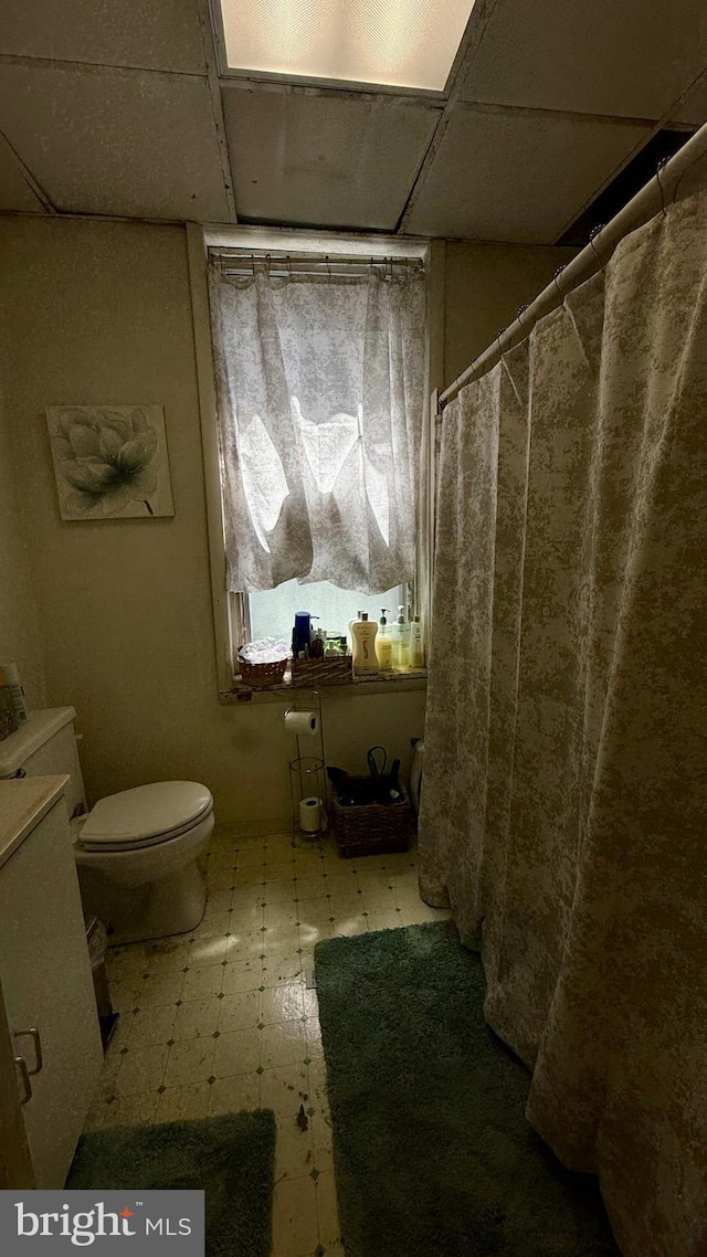 full bath featuring tile patterned floors, toilet, a paneled ceiling, and a shower with shower curtain