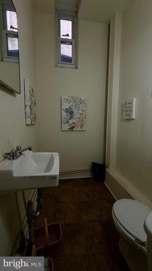 bathroom featuring toilet, plenty of natural light, and a sink