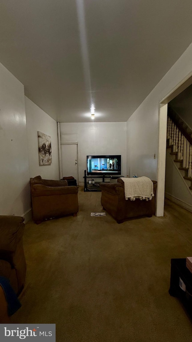 living area featuring stairs and carpet