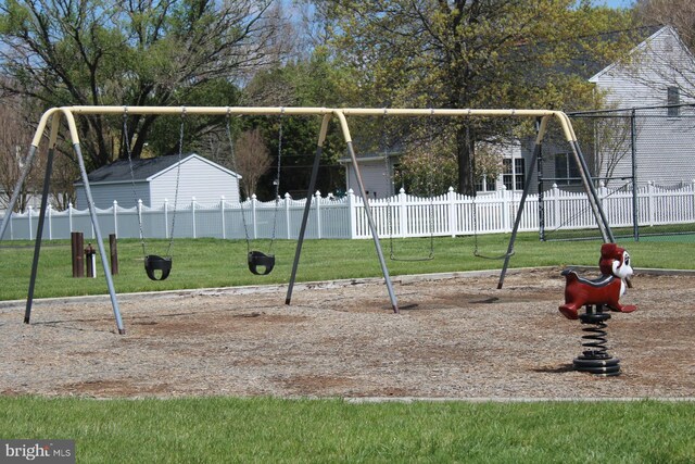 communal playground featuring a lawn and fence
