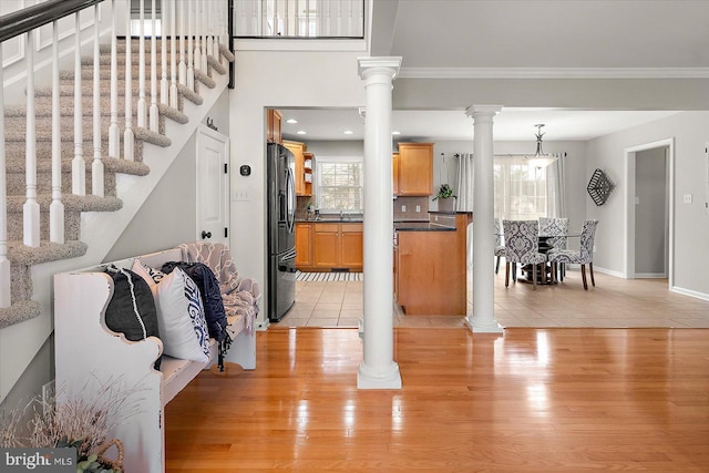 entrance foyer featuring light wood-type flooring, plenty of natural light, stairs, and ornate columns