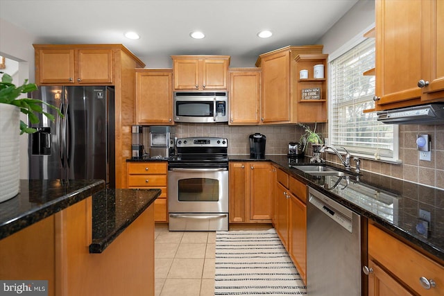 kitchen with a sink, dark stone countertops, decorative backsplash, appliances with stainless steel finishes, and light tile patterned floors