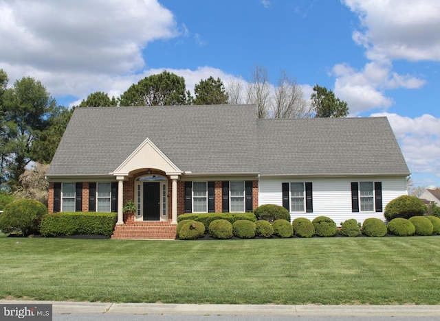 view of front facade featuring a front lawn, brick siding, and roof with shingles