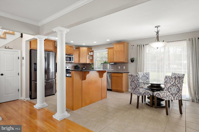 kitchen with a kitchen breakfast bar, stainless steel appliances, open shelves, dark countertops, and decorative columns