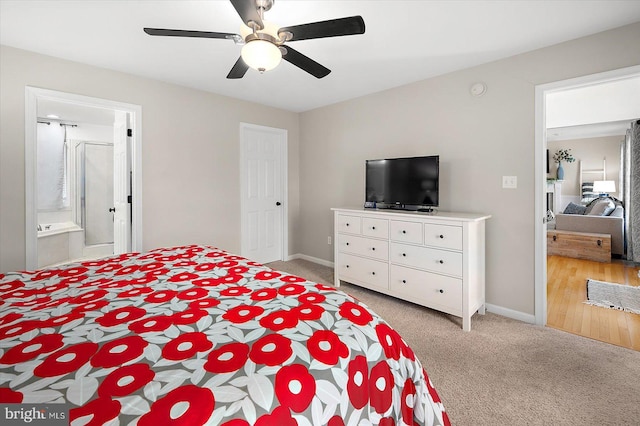 bedroom featuring light carpet, ensuite bathroom, baseboards, and ceiling fan