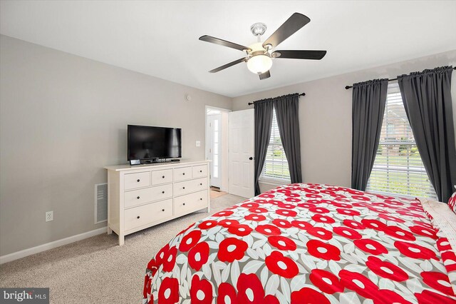 bedroom featuring baseboards, visible vents, light colored carpet, and ceiling fan