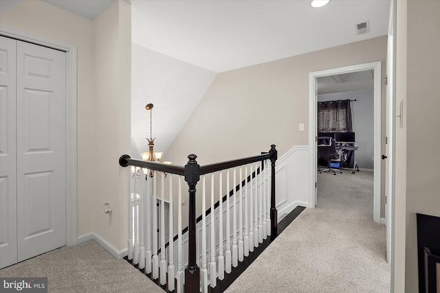 corridor featuring a notable chandelier, visible vents, dark carpet, and an upstairs landing