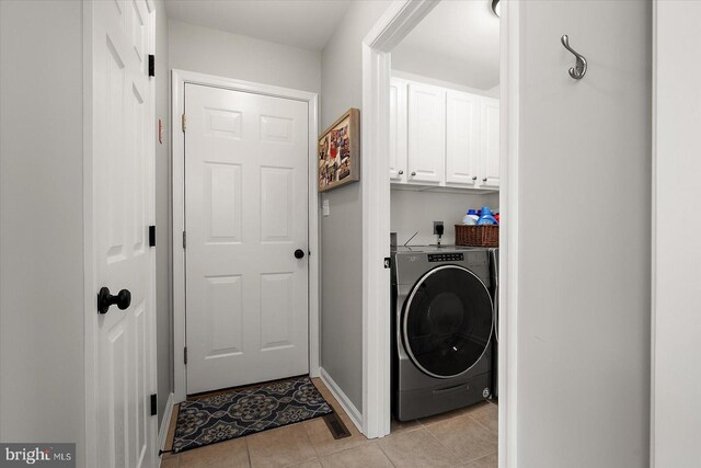laundry room featuring cabinet space, baseboards, light tile patterned flooring, and washer / clothes dryer