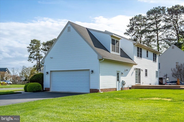 view of side of property featuring a garage, driveway, roof with shingles, and a lawn