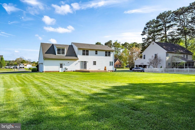 rear view of house with a wooden deck, a yard, and fence