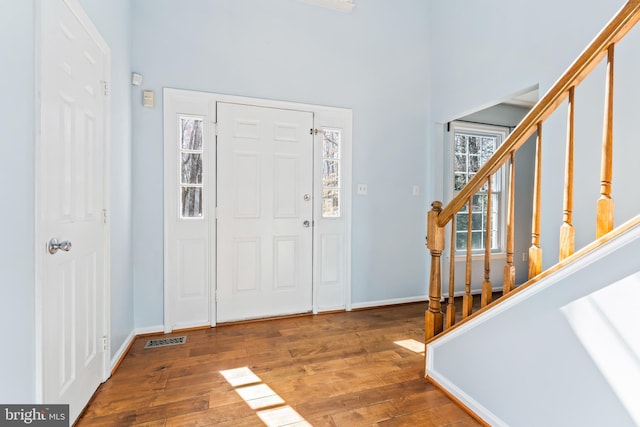 entrance foyer with wood-type flooring, baseboards, stairs, and visible vents