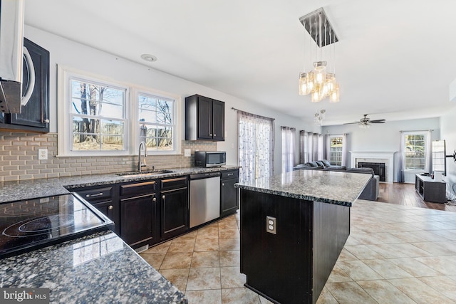kitchen featuring light tile patterned floors, a sink, stone countertops, appliances with stainless steel finishes, and a fireplace