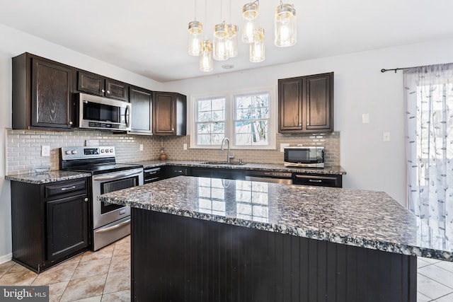 kitchen with light tile patterned flooring, dark stone counters, tasteful backsplash, appliances with stainless steel finishes, and a sink