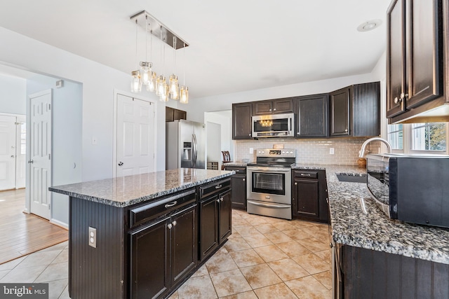 kitchen with dark stone counters, a sink, stainless steel appliances, and tasteful backsplash