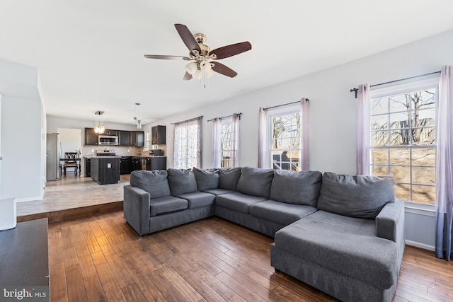 living area with hardwood / wood-style floors, baseboards, and ceiling fan