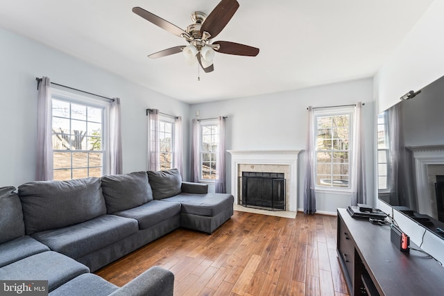 living area with baseboards, a fireplace, ceiling fan, and hardwood / wood-style flooring