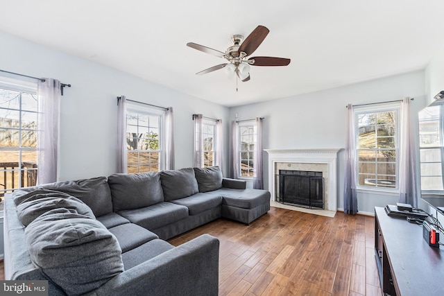 living area with baseboards, a fireplace, wood finished floors, and ceiling fan