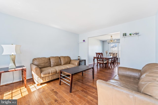 living room featuring baseboards, a notable chandelier, and wood-type flooring