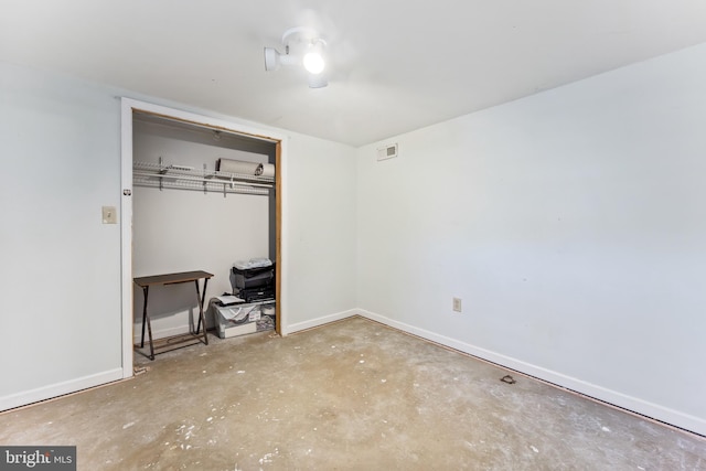 unfurnished bedroom featuring unfinished concrete flooring, baseboards, visible vents, and a closet