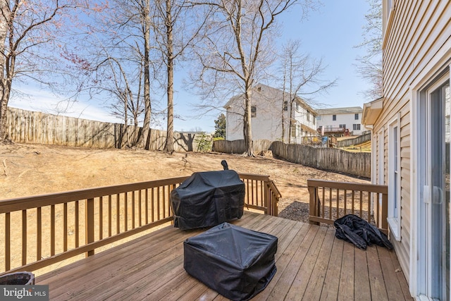 wooden terrace with a fenced backyard and a grill