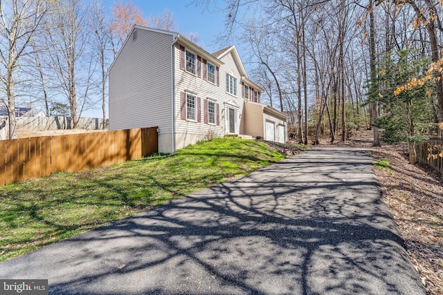 view of home's exterior with a yard, a garage, aphalt driveway, and fence