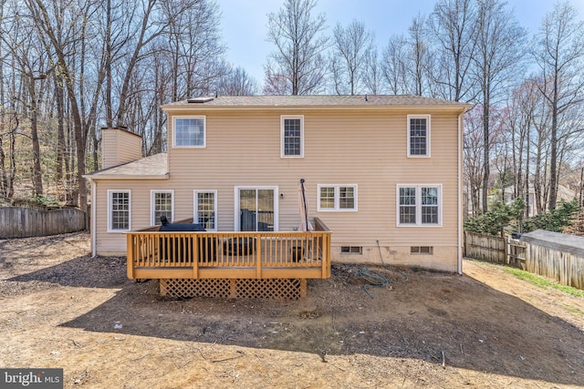 rear view of property featuring a chimney, a wooden deck, and fence