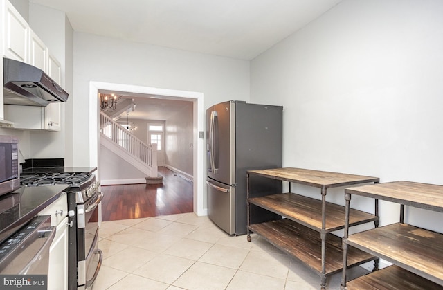 3524 Hickory Ave, Baltimore, MD 21211 - kitchen featuring light tile patterned flooring, a chandelier, white cabinetry, under cabinet range hood, and stainless steel appliances