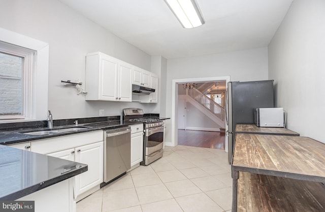 3524 Hickory Ave, Baltimore, MD 21211 - kitchen featuring stainless steel appliances, under cabinet range hood, white cabinetry, a sink, and light tile patterned floors