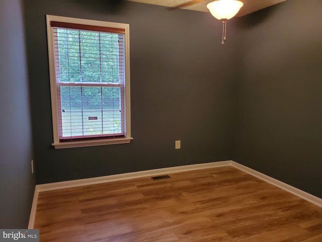 unfurnished room with visible vents, baseboards, and wood finished floors