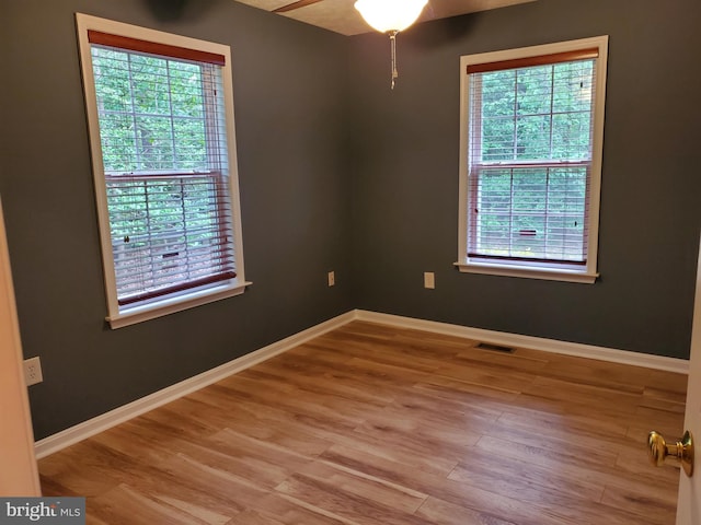 empty room featuring a ceiling fan, baseboards, light wood finished floors, and visible vents