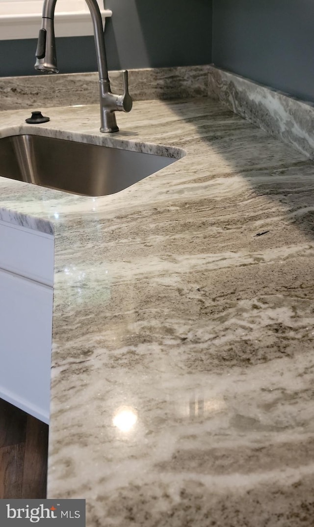 details featuring a sink and light stone countertops