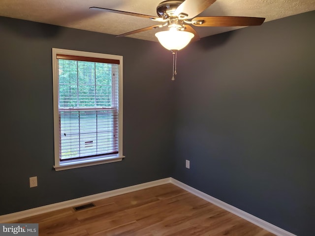 unfurnished room featuring a textured ceiling, visible vents, baseboards, ceiling fan, and wood finished floors