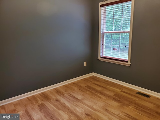 spare room featuring baseboards, visible vents, and wood finished floors