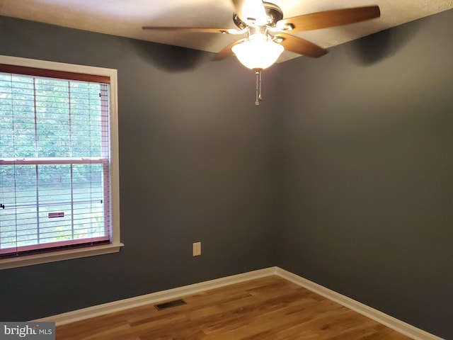 empty room with baseboards, visible vents, wood finished floors, and ceiling fan