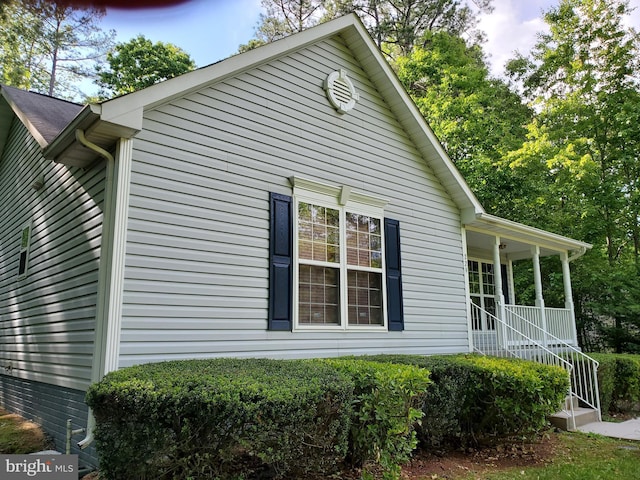 view of side of home featuring covered porch and stairway