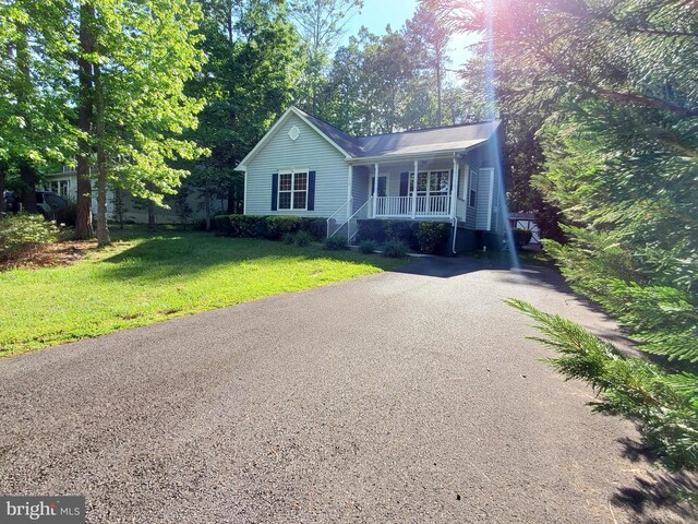 ranch-style house featuring driveway, a front lawn, and a porch