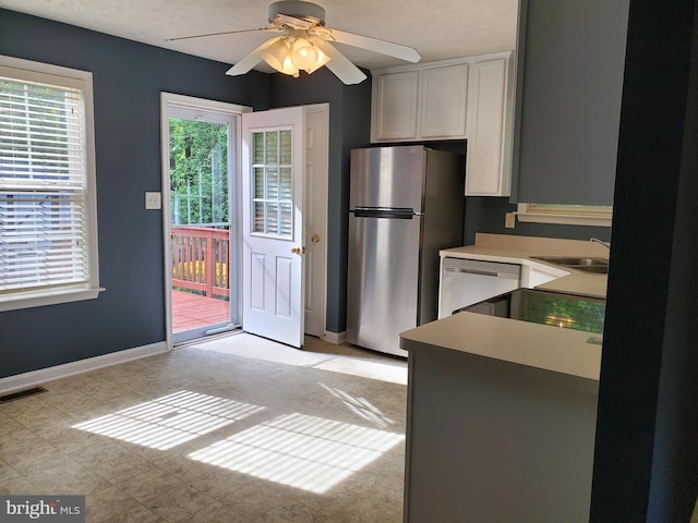 kitchen featuring visible vents, ceiling fan, a sink, white dishwasher, and freestanding refrigerator