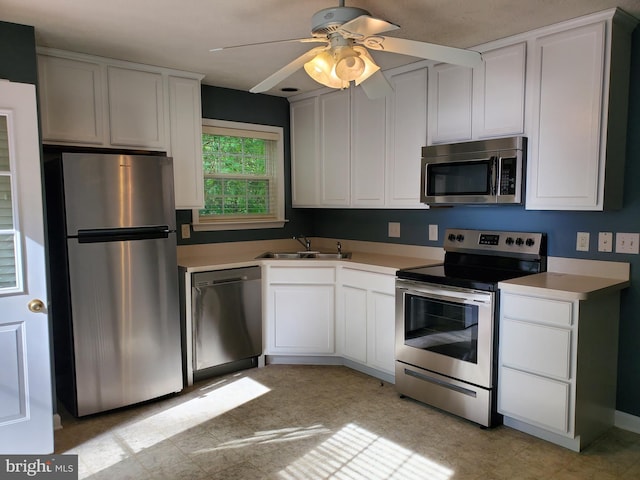 kitchen featuring light countertops, stainless steel appliances, a sink, a ceiling fan, and light floors