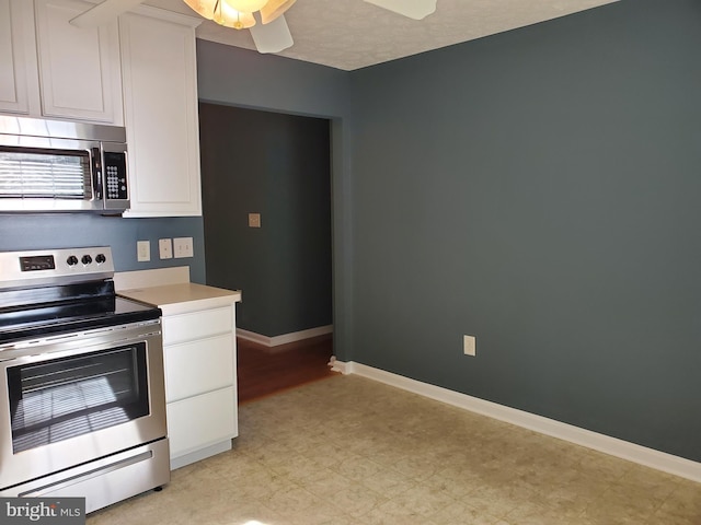 kitchen featuring light countertops, white cabinets, stainless steel appliances, and baseboards